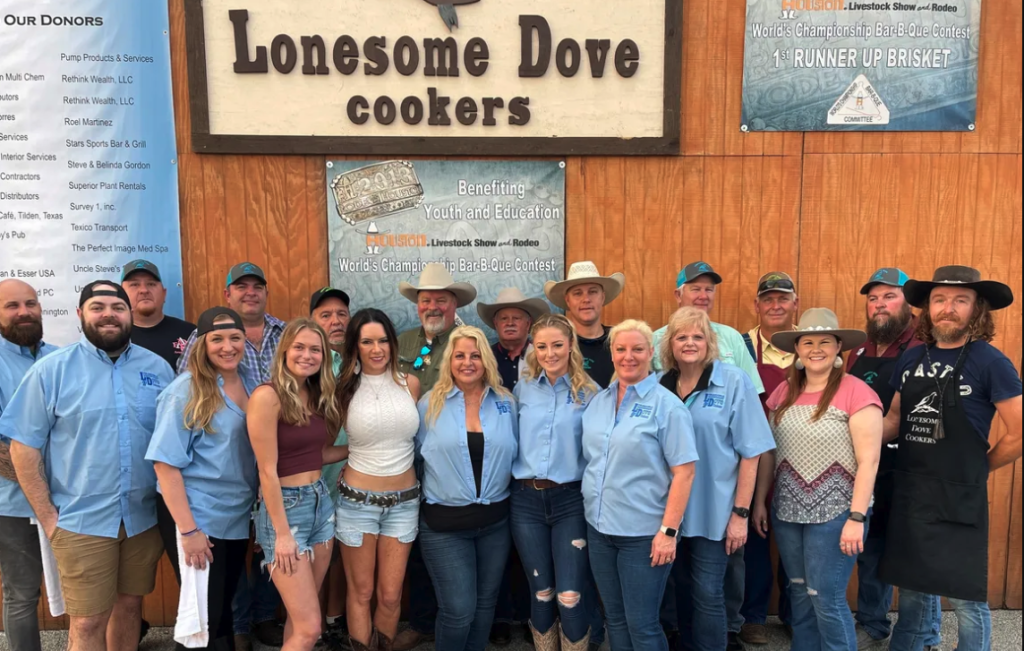 A group of people standing in front of a sign that says Lonesome Dove Cooks at the Houston Livestock Show and Rodeo.