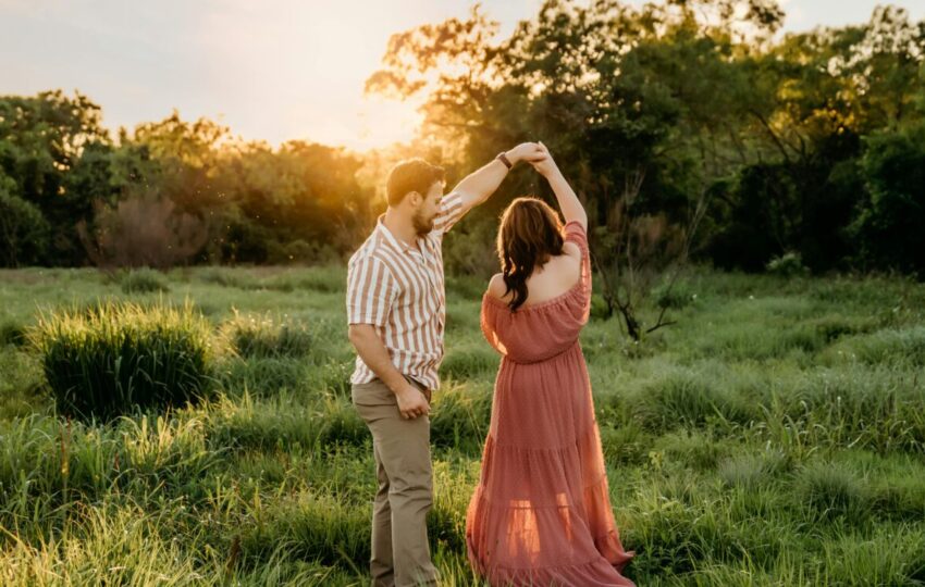 A couple gracefully dancing in a field at sunset, perfect for Valentine's Day.