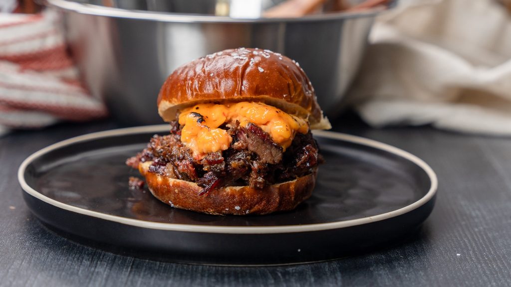 Gourmet burger with melted cheese served on a black plate.